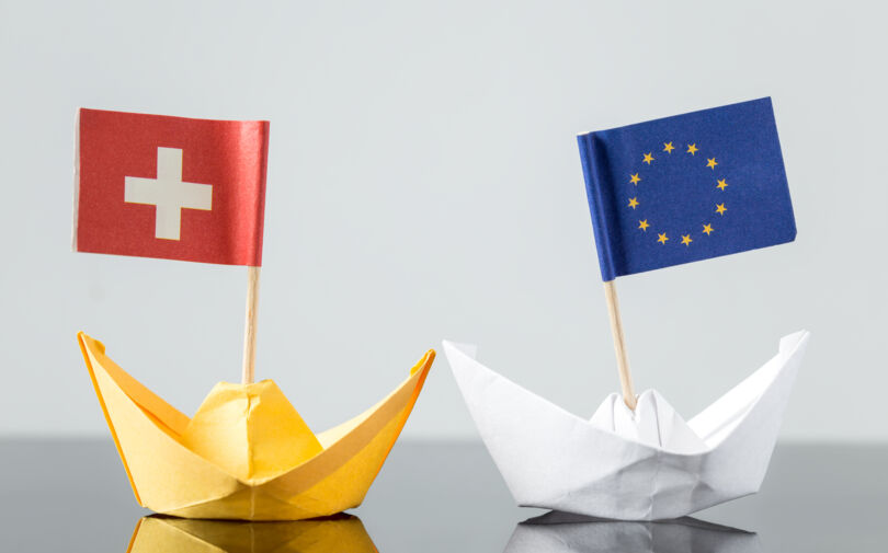 Papierschiffchen mit EU und Schweiz Flagge in Bewegung